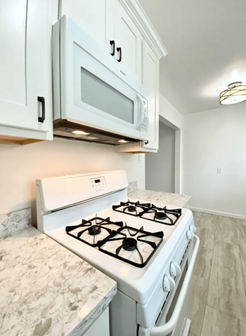 Spacious Kitchen with Stunning White Cabinetry, Gas Range, and Microwave at Jefferson Street Apartments in  Santa Clara, CA