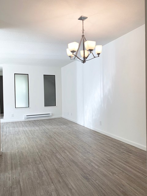 an empty living room with wood flooring and a chandelier