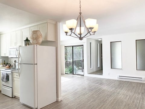 an open kitchen and living room with white cabinets and a refrigerator