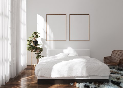 a bedroom with a white bed and two pictures on the wall