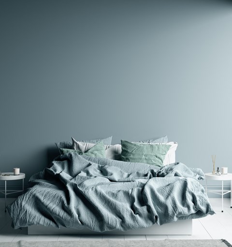 a bedroom with a blue wall and a bed with a blanket on it