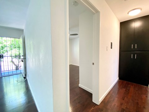 a renovated living room and hallway with wood floors and white walls