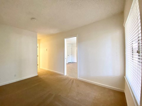 the living room and dining room of an empty apartment with white walls