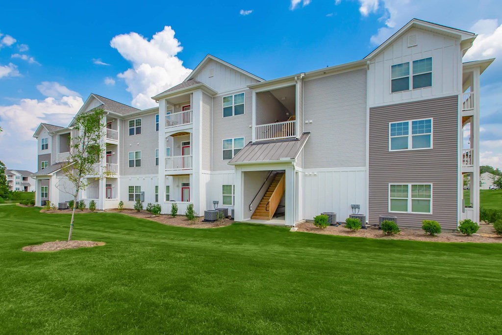 A large white apartment building with a green lawn in front.