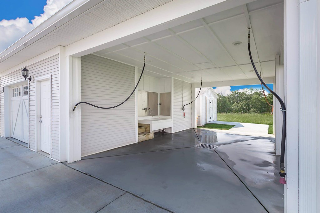 A white garage with a black hose hanging from the ceiling.