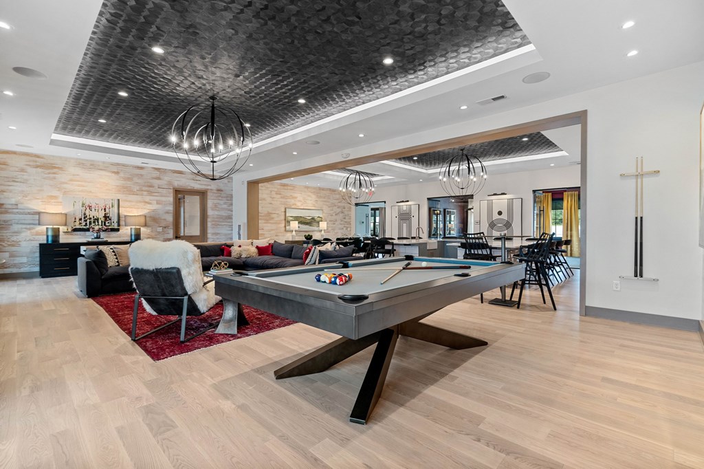 A billiard table is in the middle of a room with a chair and a pool table.