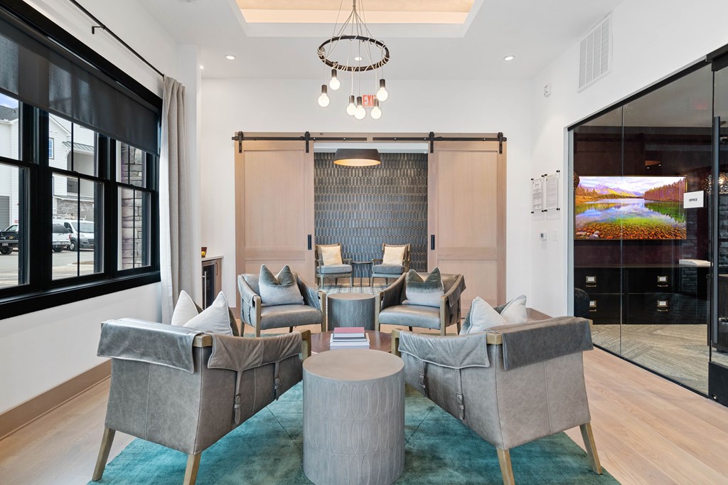 A modern living room with grey chairs and a round table.