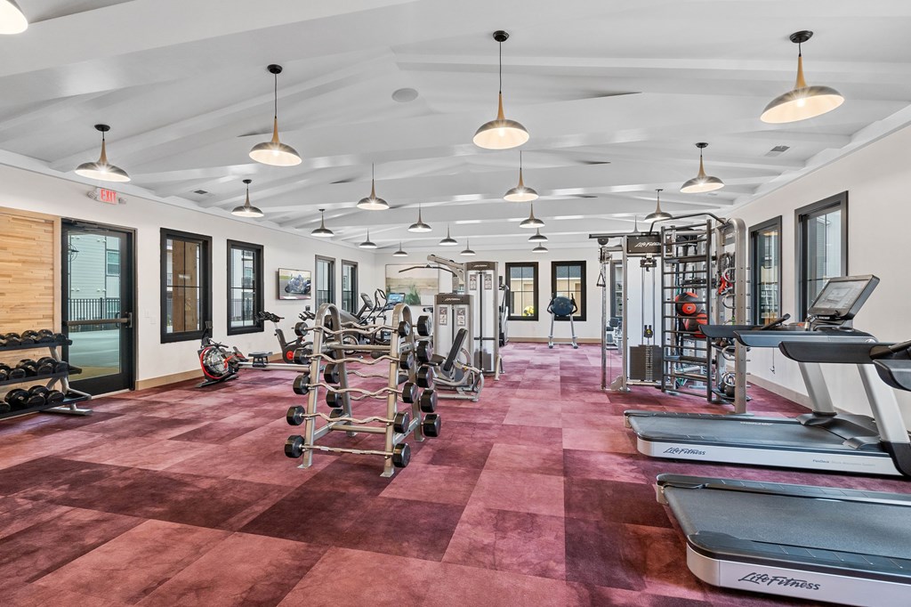 A gym with a variety of equipment including treadmills, weights, and exercise machines.