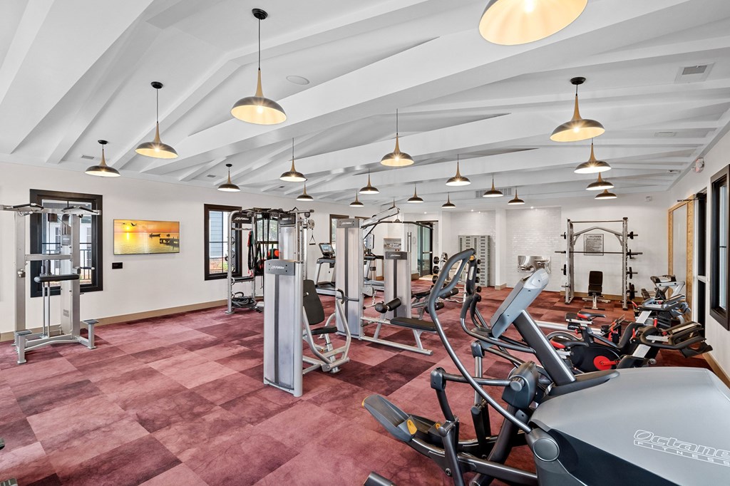 A gym with a variety of equipment including treadmills, weights, and exercise machines.