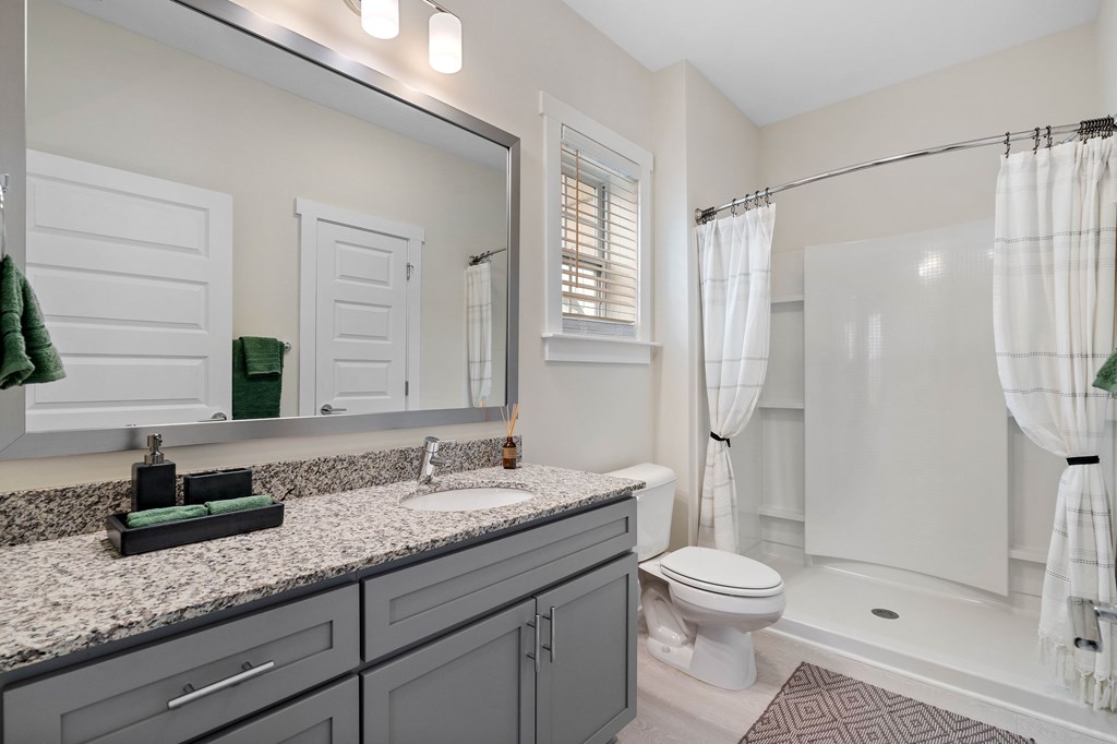 A bathroom with a white toilet, sink, and shower.