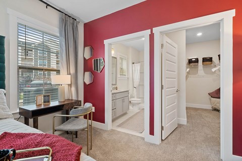 A bedroom with a red accent wall and a white door leading to a bathroom.at 198 Milltown Apartments, Burlington, NC  