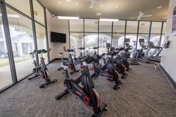 A gym with a row of stationary bikes.