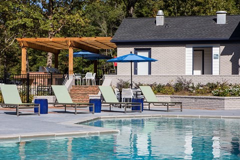 a swimming pool with chairs and umbrellas next to a house at Inverness Cliffs, Alabama