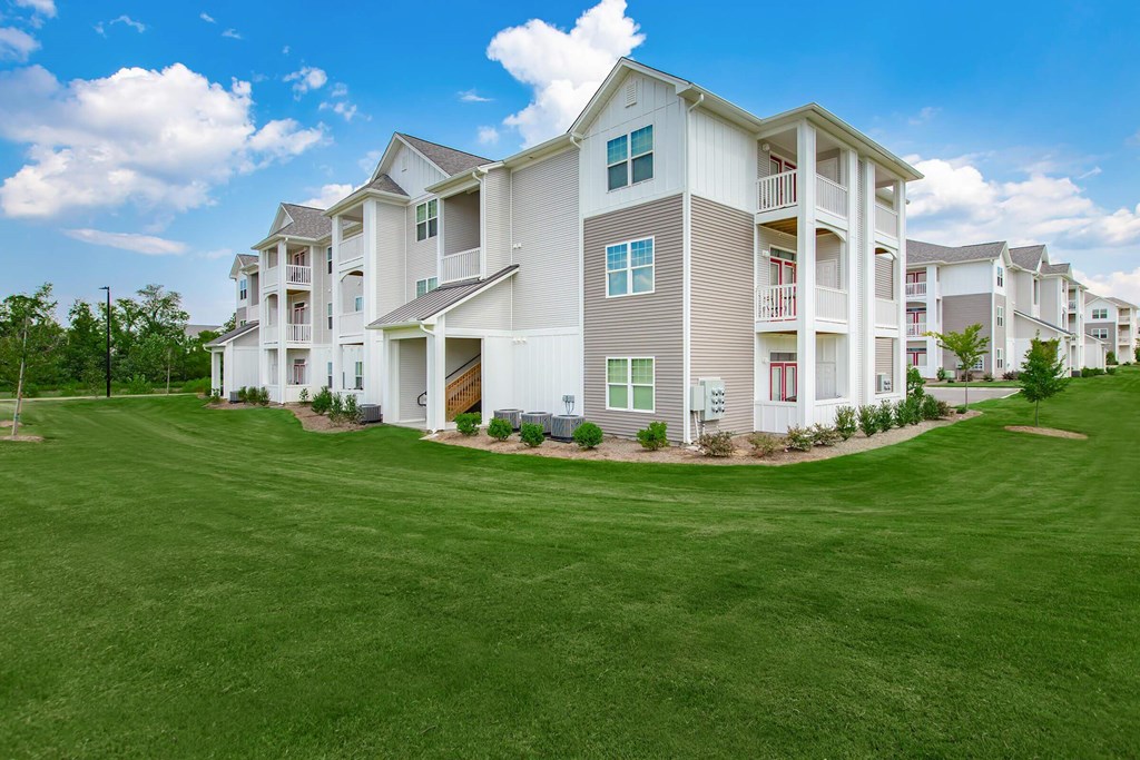 A large white apartment building with a green lawn in front.