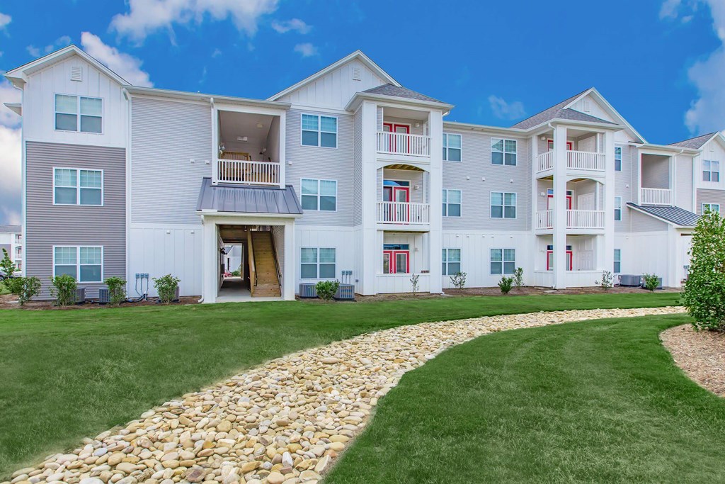 A large white apartment building with a stone pathway leading to the entrance.