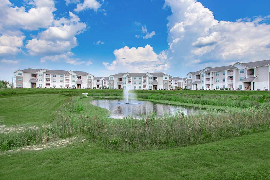 A large white building with a pond in front of it.