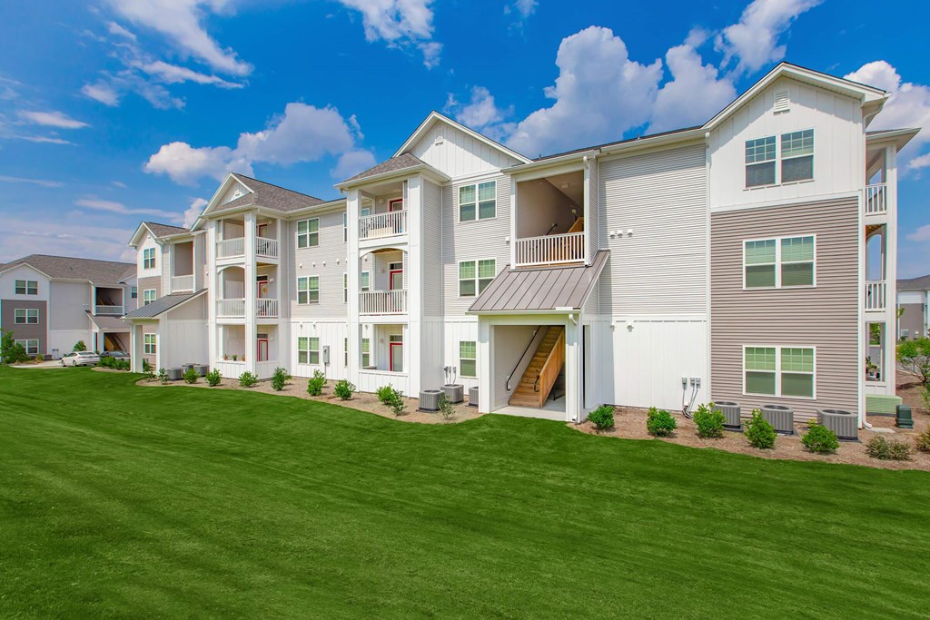 A large, modern apartment building with a green lawn in front.
