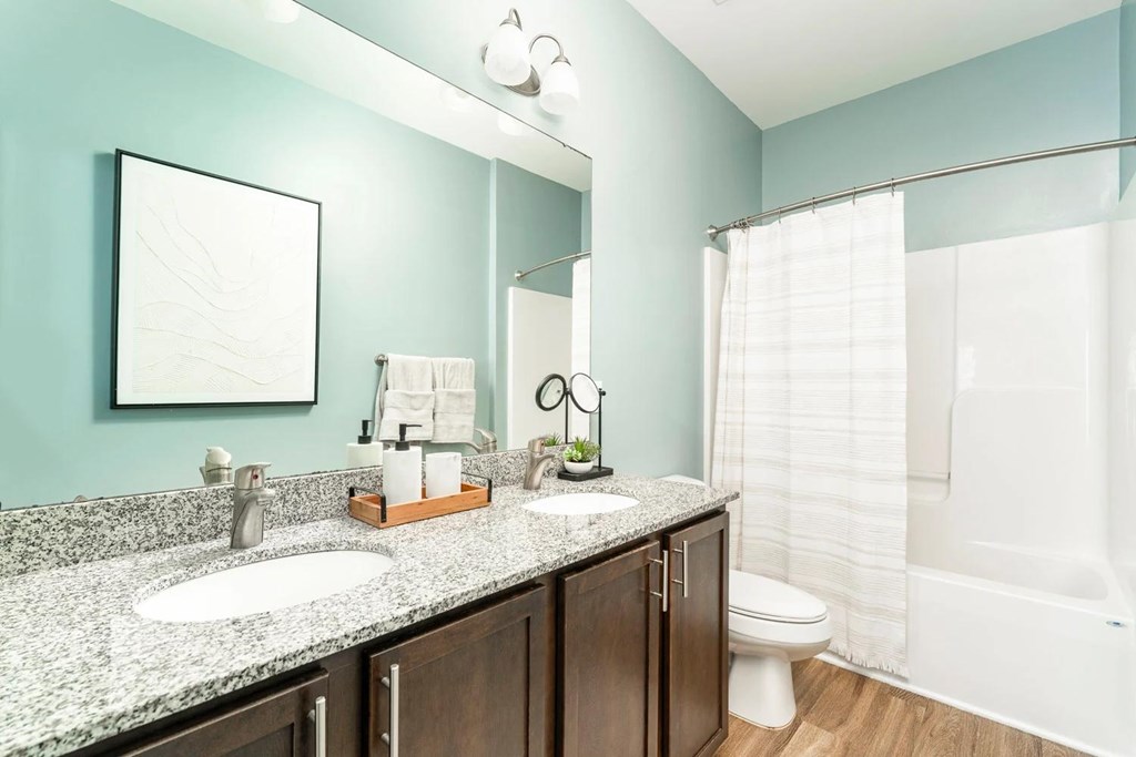 A bathroom with a sink, mirror, toilet, and shower.