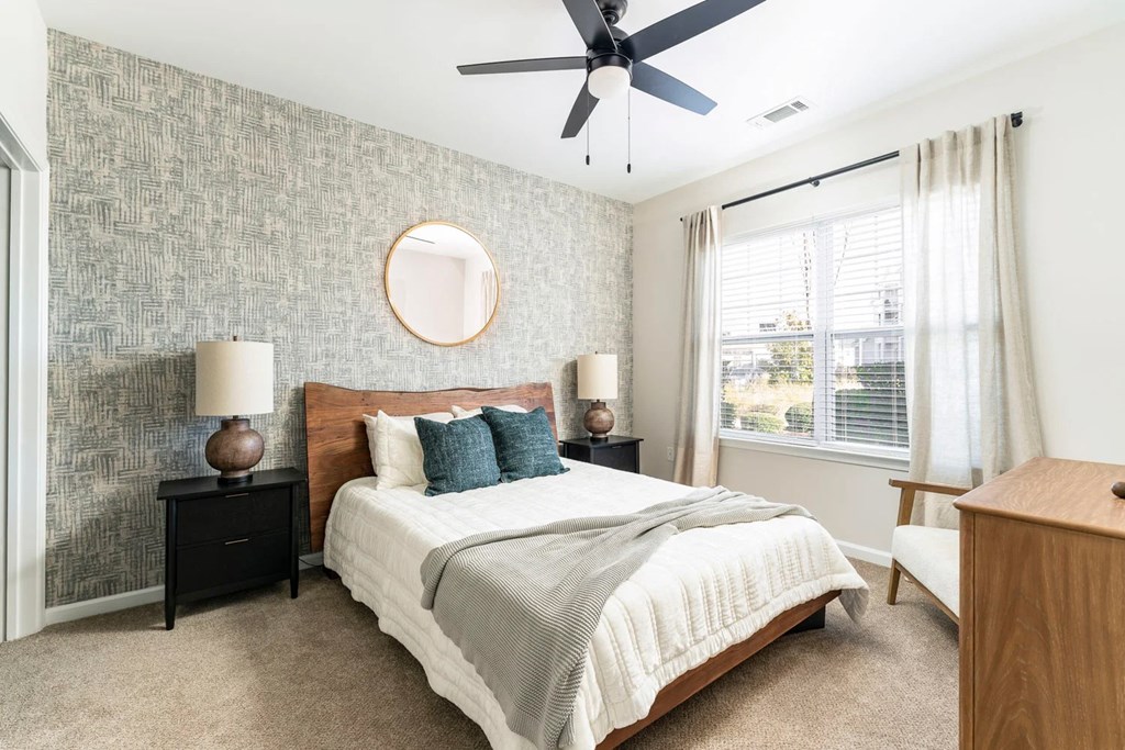 A bedroom with a bed, nightstands, and a ceiling fan.