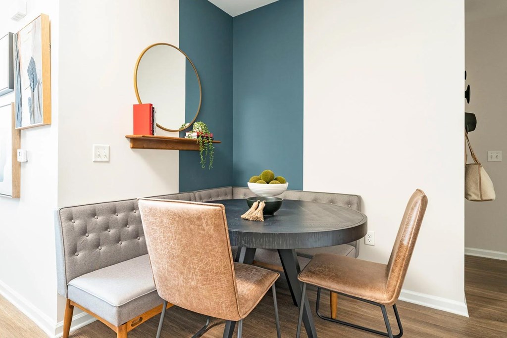 A grey chair with a tufted back sits in front of a round table.