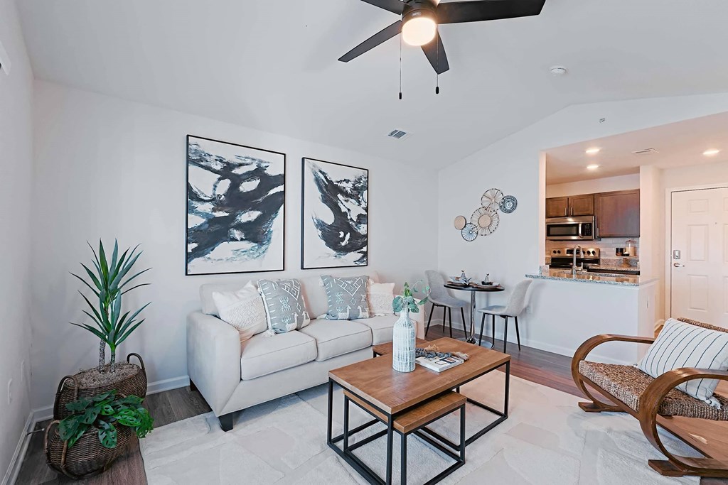 A living room with a white couch, a wooden coffee table, and a ceiling fan.