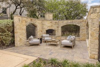 A patio with a stone wall and a fireplace.