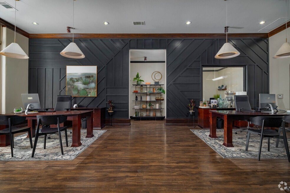 A modern office with dark wood floors and furniture.