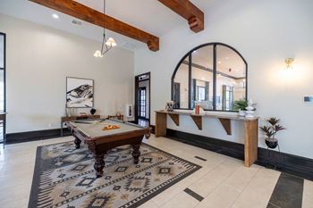 A pool table is in the middle of a room with a mirror and a bench.