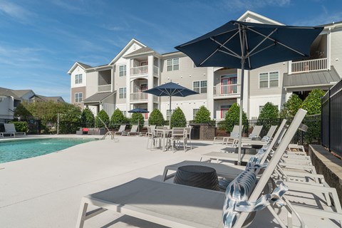 A sunny day at the pool with lounge chairs and umbrellas. at Concord Ridge Apartments, North Carolina