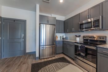 A kitchen with stainless steel appliances and wooden floors. at Magnolia Grove Apartments, Texas