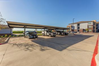 A parking lot with cars parked under a canopy. at Magnolia Grove Apartments, Terrell, TX