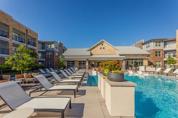 A pool area with sun loungers and a building in the background. at Magnolia Grove Apartments, Terrell, 75160