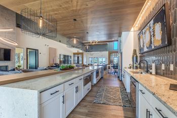 A modern kitchen with a long counter and a rug on the floor. at Magnolia Grove Apartments, Terrell