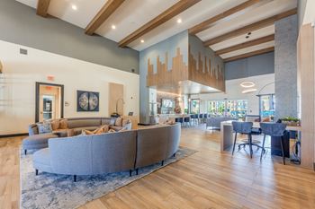 A spacious living room with a grey sofa and wooden floors. at Magnolia Grove Apartments, Texas, 75160