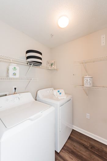 A white washing machine and dryer in a small laundry room. at WildForest Apartments, Birmingham, AL, 35209