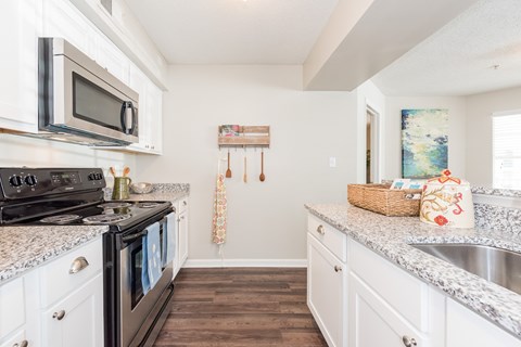 A kitchen with a black stove top oven and white cabinets. at WildForest Apartments, Birmingham, AL