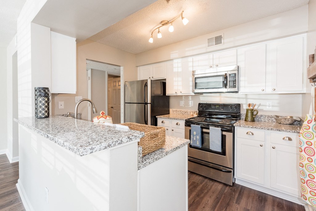 A kitchen with white cabinets and a granite countertop. at WildForest Apartments, Birmingham, Alabama