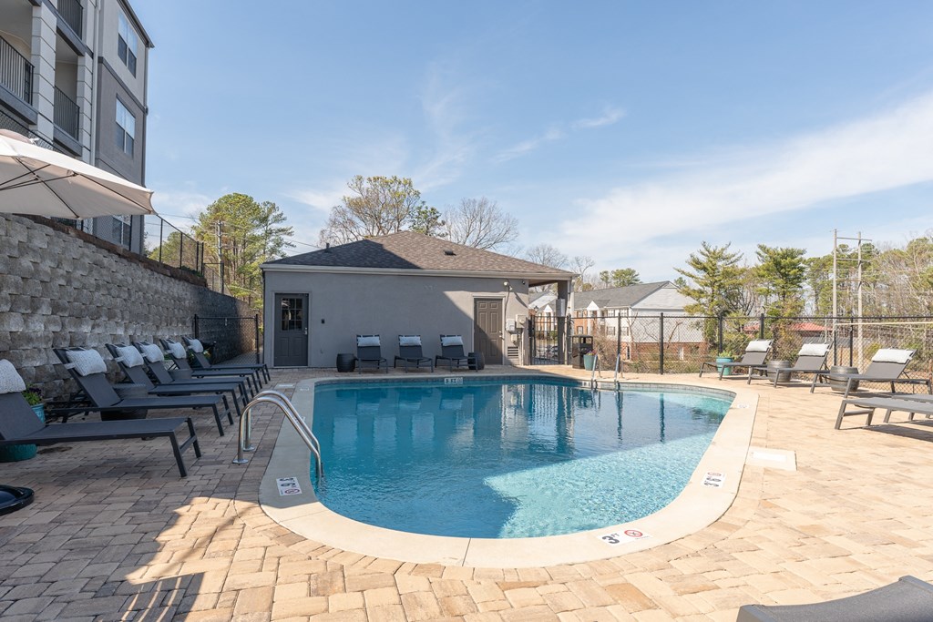 a swimming pool with lounge chairs and a building in the background at WildForest Apartments, Birmingham, AL