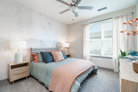 A bedroom with a bed, nightstands, and a ceiling fan.