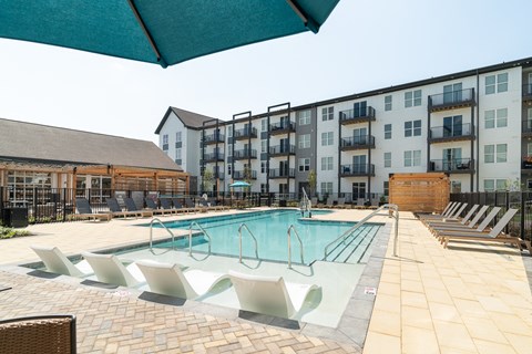 A large swimming pool with lounge chairs and a building in the background.