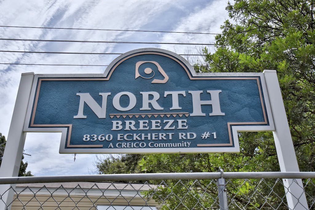 a blue sign with a fence and trees