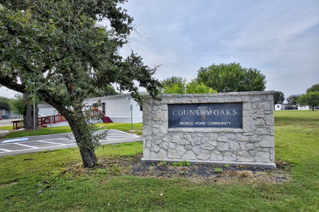 a stone monument with a navy blue sign and a tree in front of it