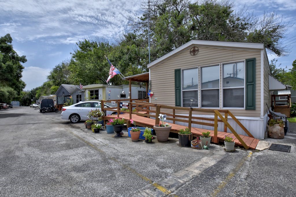 a small house with potted plants in front of a parking lot
