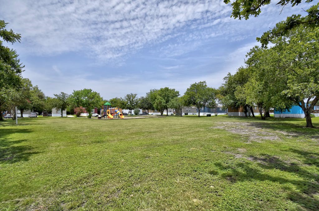a large grassy area with a playground in the distance