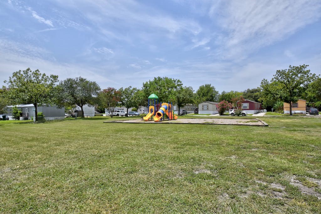 a large grassy area with a playground in the middle of it