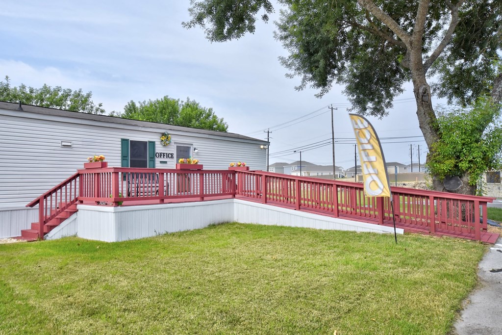 a large white building with a red deck and a large tree in front of it
