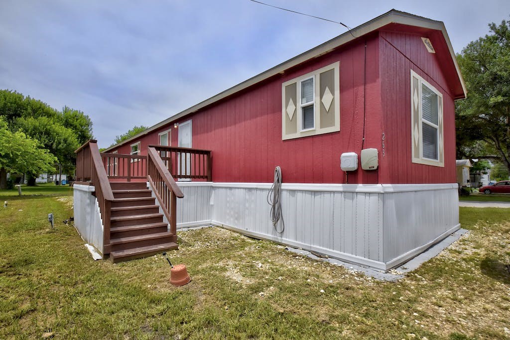 a red house with a wooden deck and a white fence