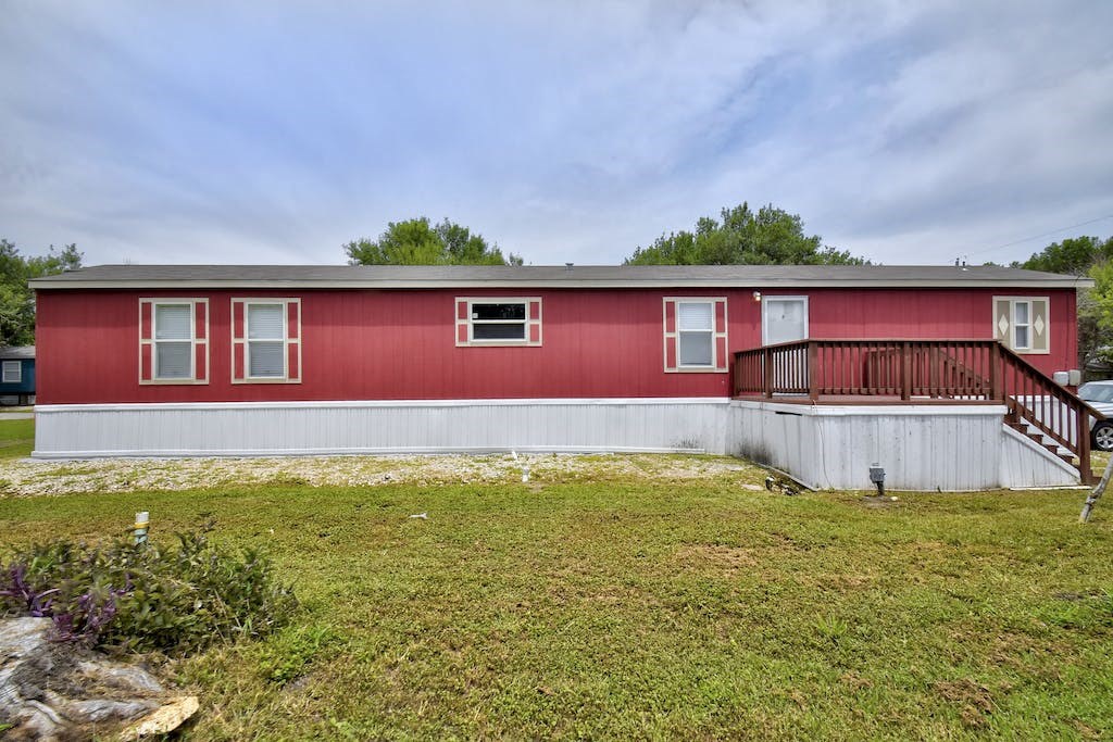 a red house with a white exterior and a green yard