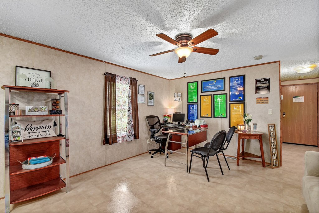 a living room with a ceiling fan and a desk with a computer