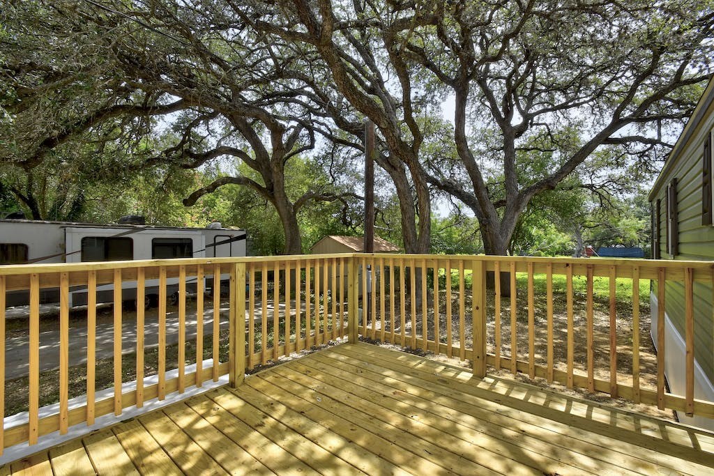 large deck with trees and a rv in the background